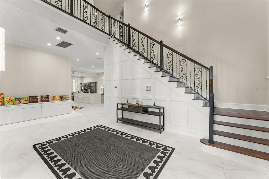 A bright foyer features white marble floors, a staircase with iron railings, and wainscoting — 6288 BLAKEFORD DRIVE, WINDERMERE, FL