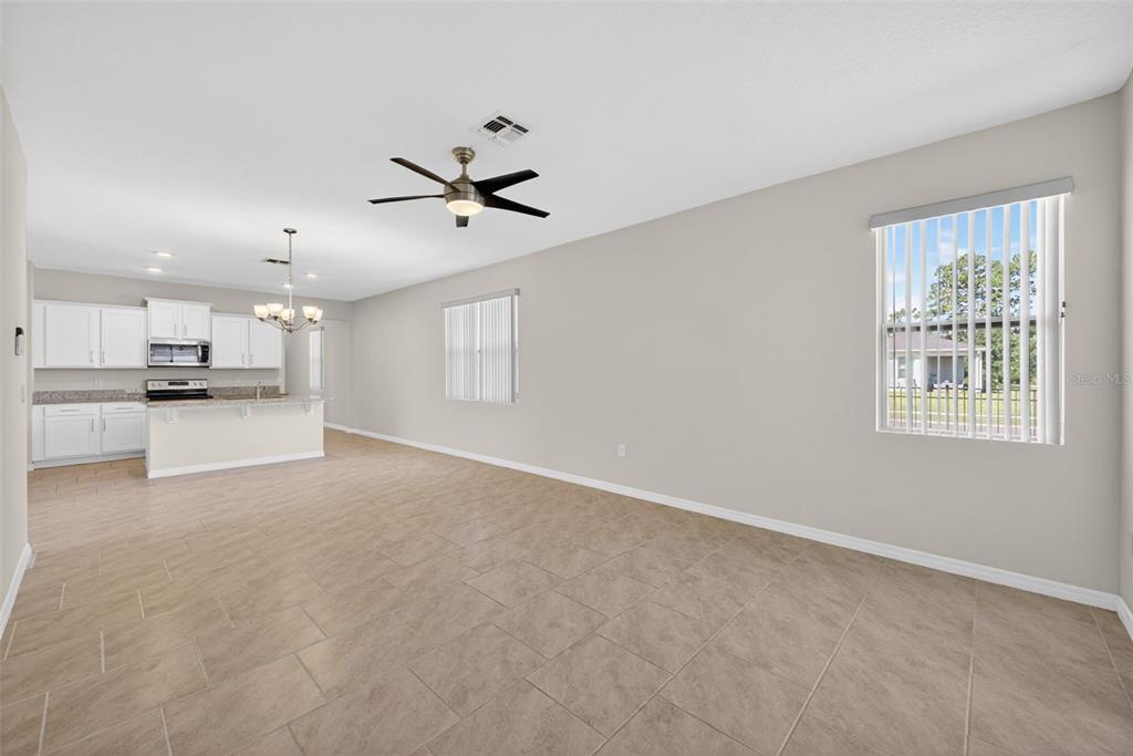 An open-concept living and dining area features a sectional sofa, dining table, and kitchen — 17386 BLAZING STAR CIRCLE, CLERMONT, FL