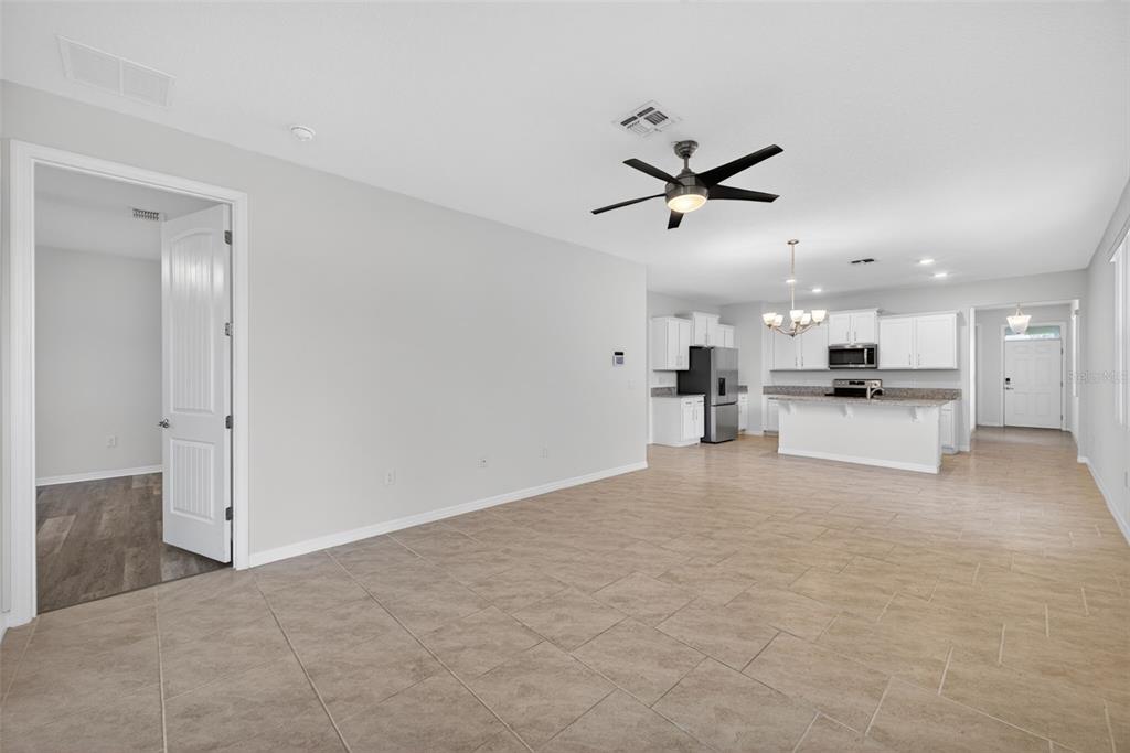 An open-concept living area with tile flooring, a ceiling fan, and an adjacent kitchen — 17386 BLAZING STAR CIRCLE, CLERMONT, FL