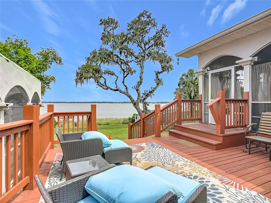 A screened-in porch features wicker furniture, a patterned rug, and a painted sky ceiling — 331 BAY STREET, AUBURNDALE, FL