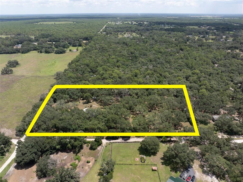 An aerial view shows a rectangular plot of land outlined in yellow amidst wooded terrain — 7224 SHAW RD., BROOKSVILLE, FL