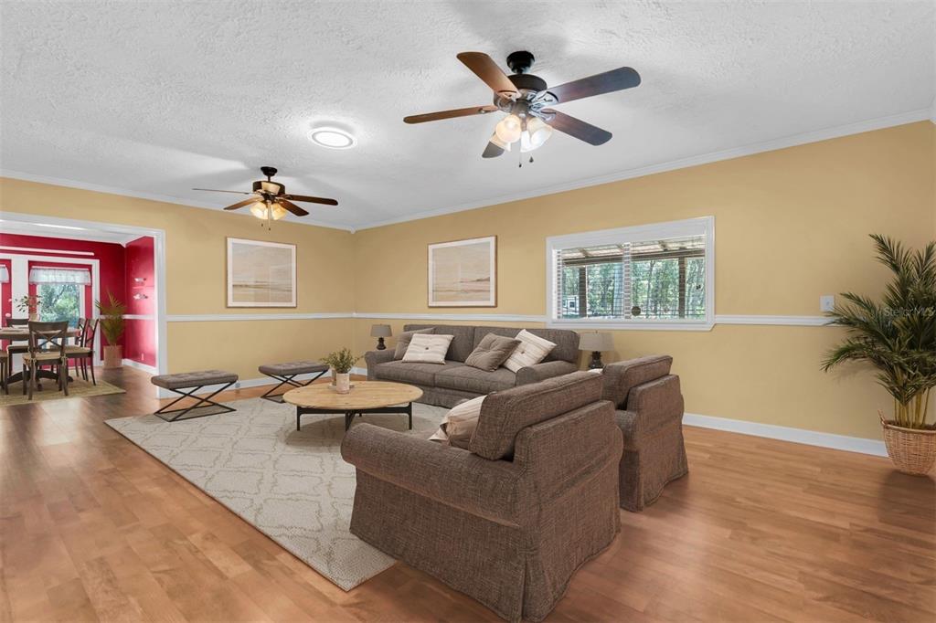 A living room with light yellow walls, wood flooring, a ceiling fan, and brown furniture — 7224 SHAW RD., BROOKSVILLE, FL