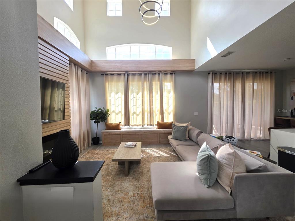 A living room features a high ceiling, a large sectional sofa, and a fireplace wall — 734 MONROE CIRCLE, DAVENPORT, FL