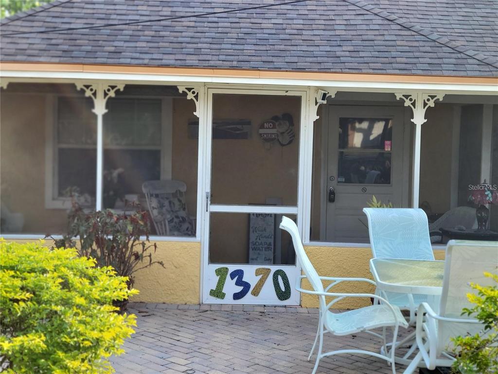 A screened-in porch features a brick patio, white patio furniture, and a numbered screen door — 1370 GREENWAY DRIVE, MOUNT DORA, FL