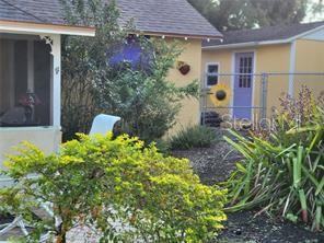 A yellow house with a purple door and a small patio area with green plants — 1370 GREENWAY DRIVE, MOUNT DORA, FL