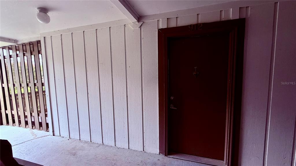 A room with light-colored tile flooring, a ceiling fan, and a doorway leading to a kitchen — 6519 W NEWBERRY ROAD UNIT 912, GAINESVILLE, FL