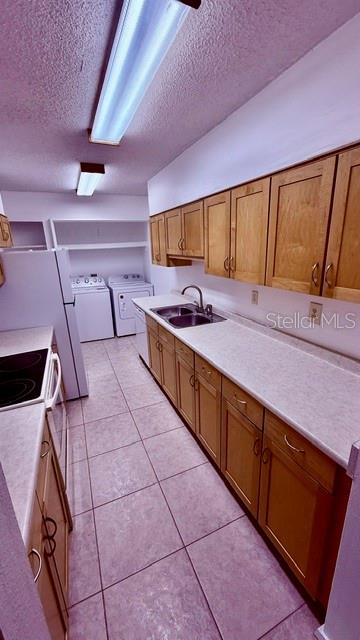A kitchen features light wood cabinets, white appliances, and tile flooring — 6519 W NEWBERRY ROAD UNIT 912, GAINESVILLE, FL