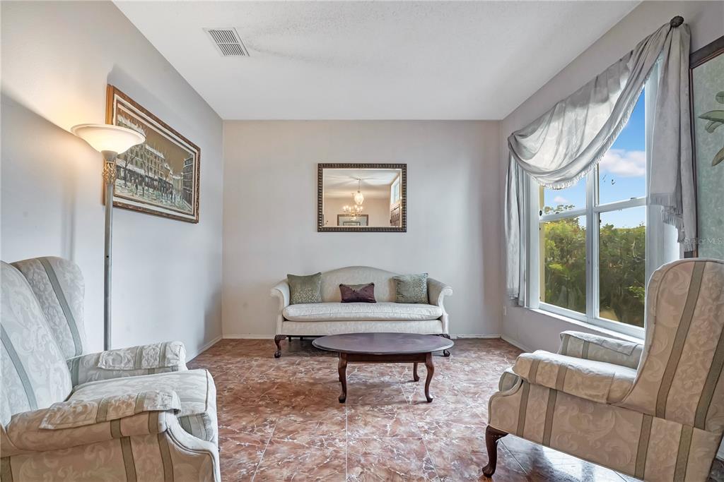 A formal living room features a sofa, two armchairs, a coffee table, and tile flooring — 1019 BRIDGEWAY BOULEVARD, ORLANDO, FL
