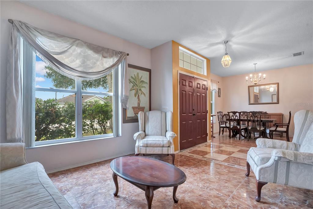 A living and dining area features tile floors, a large window, and a double front door — 1019 BRIDGEWAY BOULEVARD, ORLANDO, FL