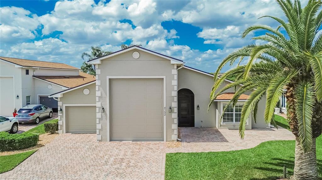 A beige house with a paved driveway, a garage, and a palm tree in the yard — 4152 DUNMORE DRIVE, LAKE WALES, FL