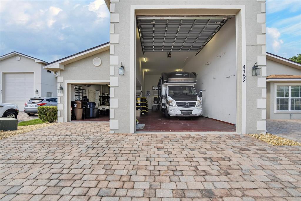 A house exterior features a tall garage bay housing a motorhome and a standard garage — 4152 DUNMORE DRIVE, LAKE WALES, FL
