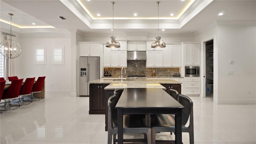 A covered patio with outdoor furniture and a kitchen overlooks a swimming pool and spa — 1253 RADIANT STREET, REUNION, FL