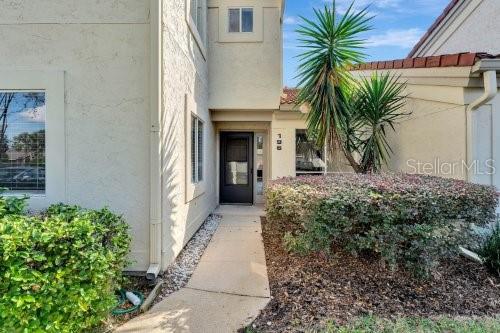 The exterior of a two-story stucco home features a front door, walkway, and landscaping — 196 W SABAL PALM PLACE UNIT 196, LONGWOOD, FL