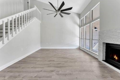 A living room features light wood flooring, a white staircase, a ceiling fan, and a fireplace — 196 W SABAL PALM PLACE UNIT 196, LONGWOOD, FL