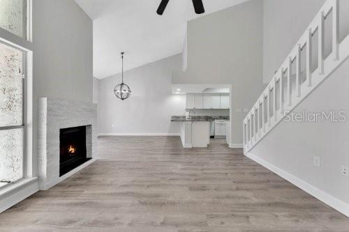 A living room with a fireplace, light wood flooring, and a staircase leading upstairs — 196 W SABAL PALM PLACE UNIT 196, LONGWOOD, FL