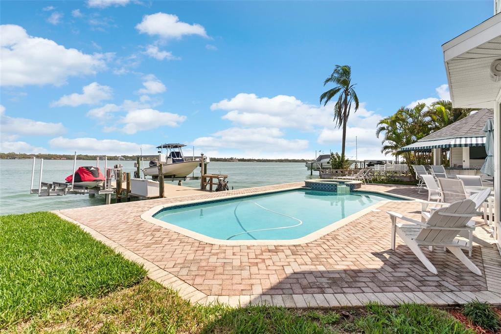 An aerial view shows a two-story house with a dark roof situated between two properties — 11445 9TH STREET E, TREASURE ISLAND, FL