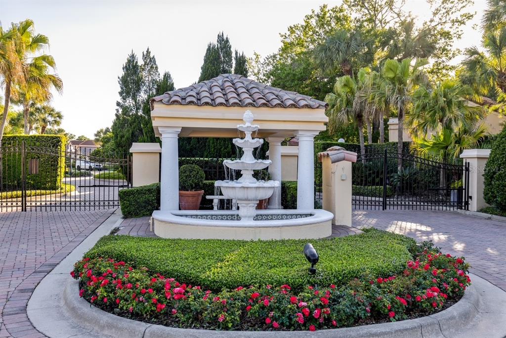 A tiered fountain sits under a gazebo at the gated entrance of a residential community — 2428 VIA GENOVA, APOPKA, FL