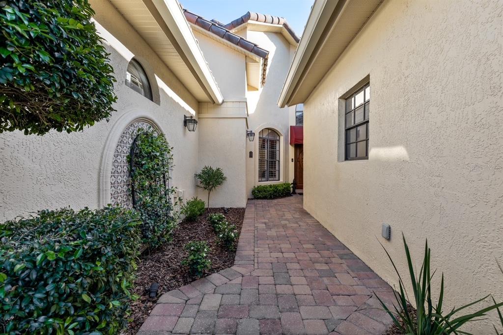 A paved walkway leads to the front entrance of a stucco home with arched windows — 2428 VIA GENOVA, APOPKA, FL