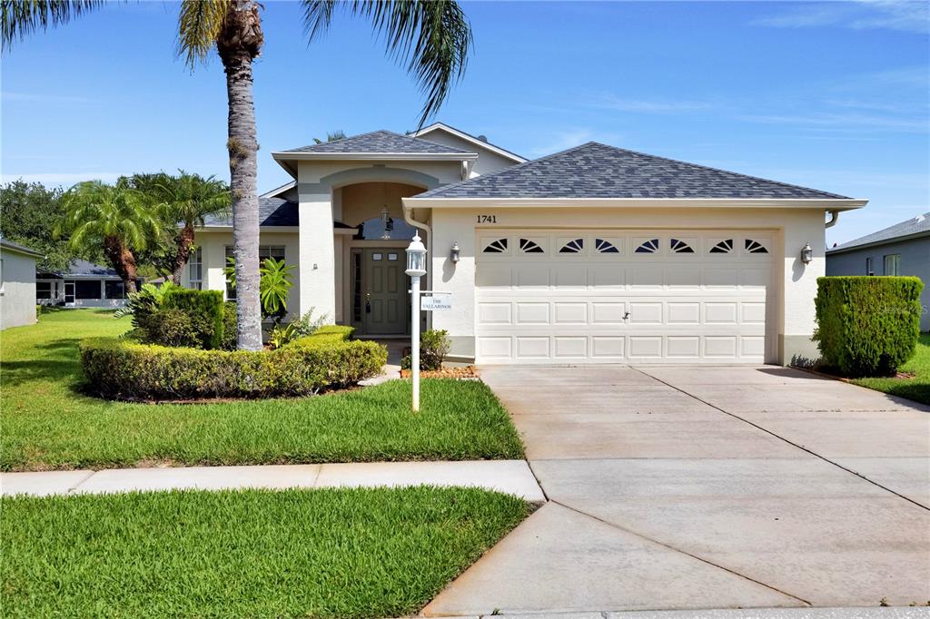 A single-story house with a two-car garage, a palm tree, and a manicured lawn — 1741 ARBOR KNOLL LOOP, TRINITY, FL