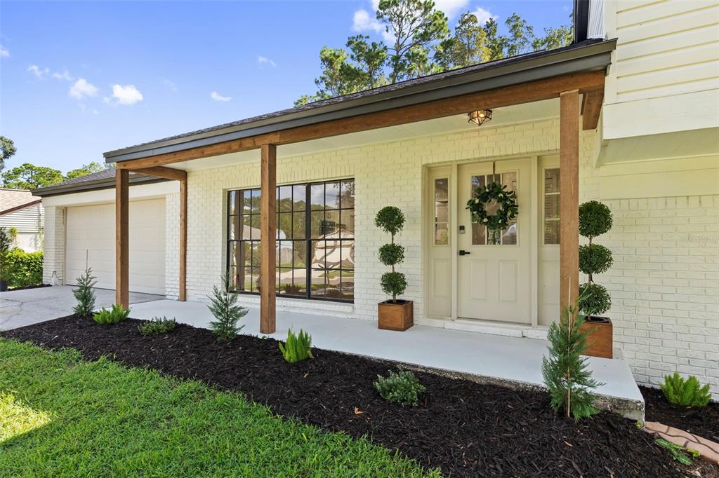 The exterior of a house features a white brick facade, a covered porch, and wood columns — 3720 MURRAY DALE DRIVE, VALRICO, FL