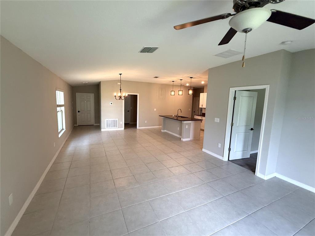 An open-concept living and dining area features light tile flooring, a kitchen island, and ceiling fans — 15516 MILLER CREEK DRIVE, SUN CITY CENTER, FL