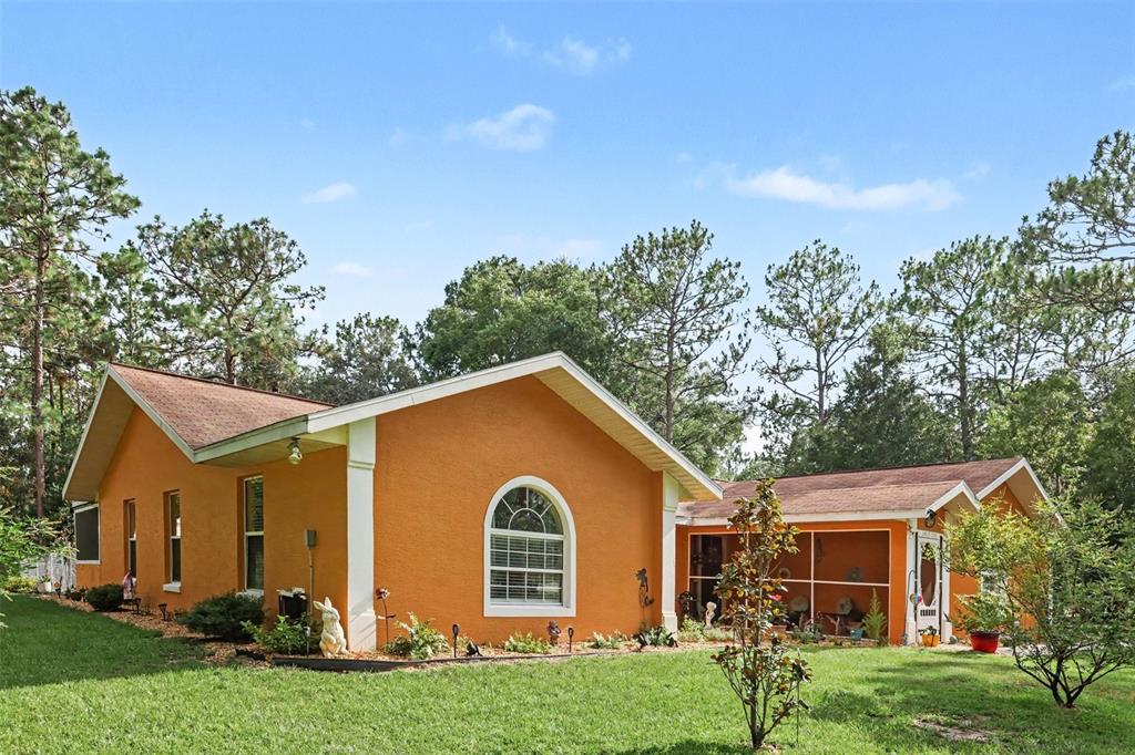 An orange stucco house with a screened-in porch and a large arched window — 18018 SW 68TH LOOP, DUNNELLON, FL