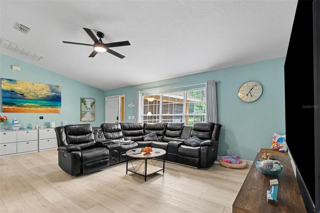 A living room features a black sectional sofa, light wood floors, and light blue walls — 18018 SW 68TH LOOP, DUNNELLON, FL