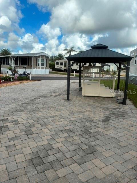 A paved driveway features a dark-roofed gazebo structure and a nearby mobile home — 2512 MAGNOLIA STREET, CLERMONT, FL