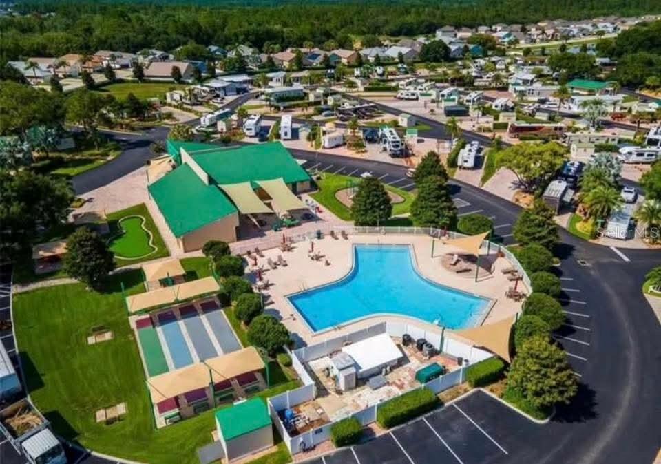 An aerial view of a community pool, clubhouse, and recreational courts surrounded by residential homes — 2512 MAGNOLIA STREET, CLERMONT, FL