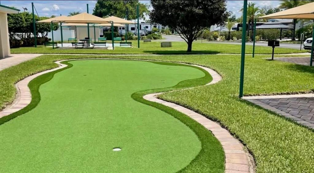 A putting green with brick paver borders sits on a lawn near a covered patio area — 2512 MAGNOLIA STREET, CLERMONT, FL
