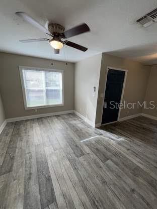 An empty room features light gray wood-look flooring, a ceiling fan, and a dark blue door — 225 1ST STREET, WINTER GARDEN, FL