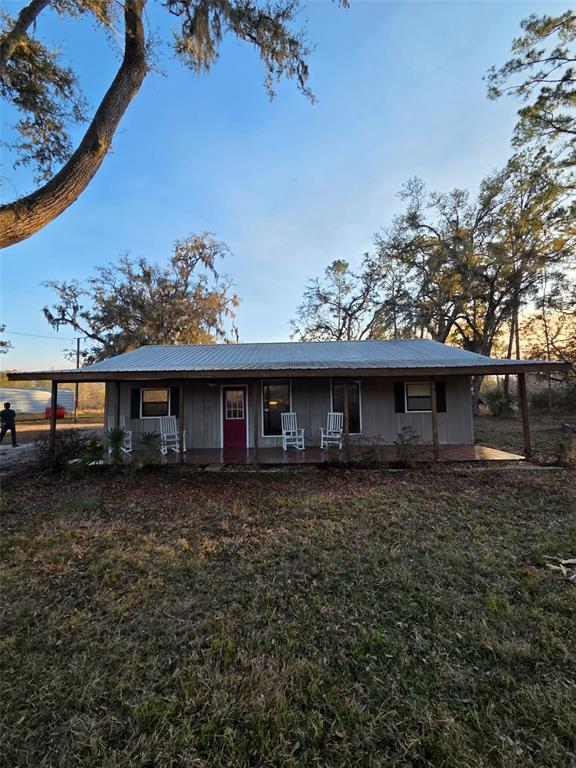 A single-story house with a metal roof and a front porch featuring white rocking chairs — 1106 FOX HUNTER RD, PERRY, FL