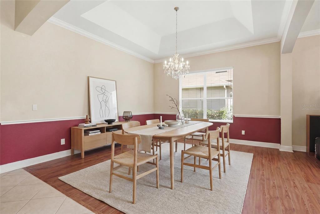 A dining room features wood flooring, a tray ceiling, a chandelier, and two-toned wall paint — 1830 BURDOCK DRIVE, WINTER GARDEN, FL