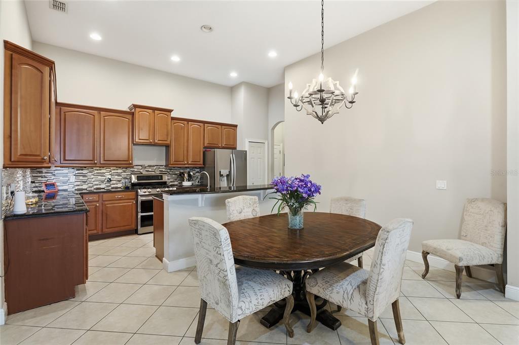 A kitchen with wood cabinets and granite countertops sits adjacent to a dining area — 1830 BURDOCK DRIVE, WINTER GARDEN, FL