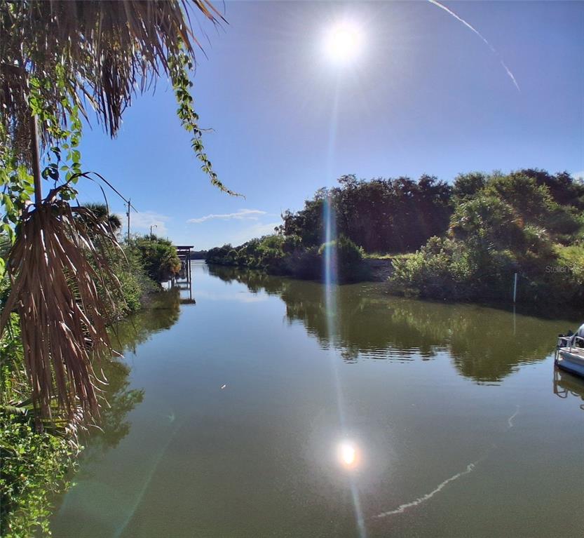 A view of a calm canal lined with lush green trees under a bright sun — 4366 WHITING WAY, EDGEWATER, FL