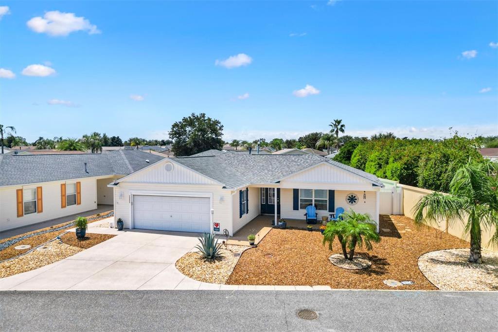 A single-story house with a white garage, light siding, and a landscaped front yard — 1026 SMYRNA STREET, THE VILLAGES, FL