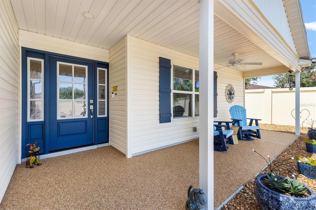 A covered front porch features a blue door, light siding, and blue Adirondack chairs — 1026 SMYRNA STREET, THE VILLAGES, FL