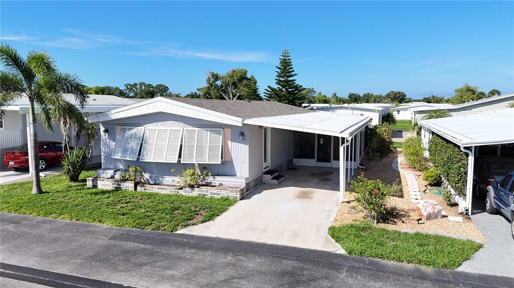 A single-story manufactured home features a white exterior, louvered shutters, and an attached carport — 3 S BUENA VISTA AVENUE, ENGLEWOOD, FL