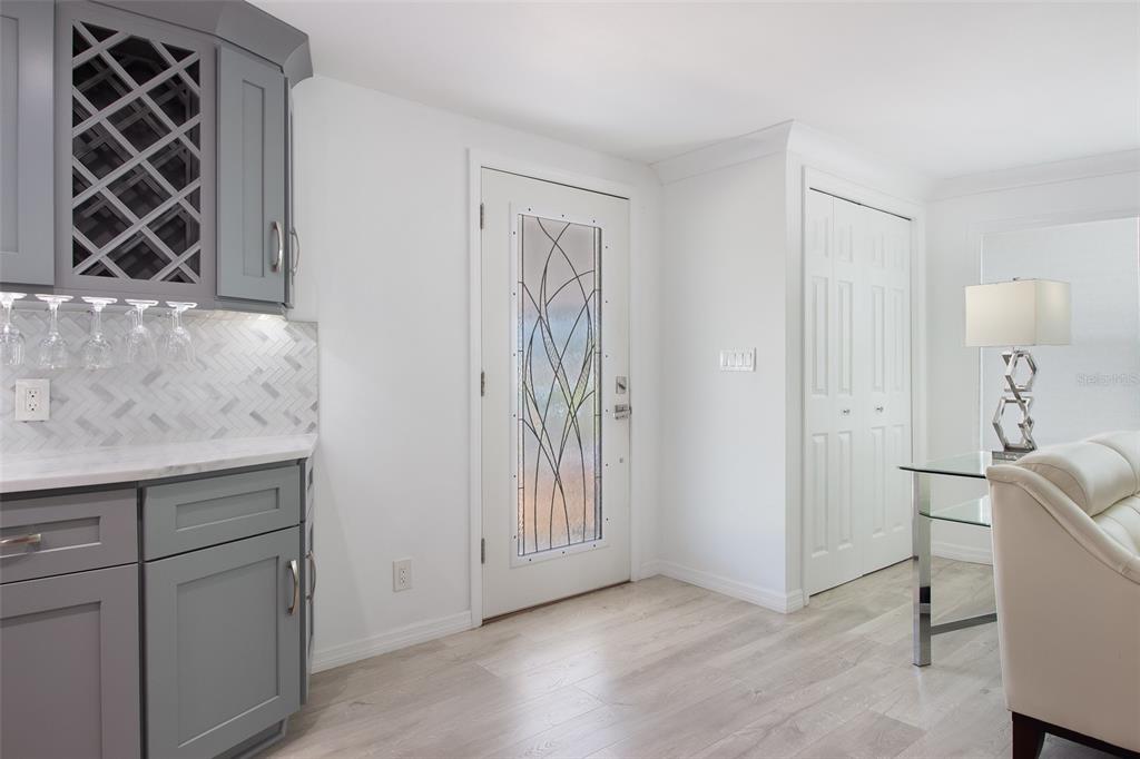 A room features gray cabinets, a wine rack, a glass-paneled door, and light wood flooring — 3 S BUENA VISTA AVENUE, ENGLEWOOD, FL