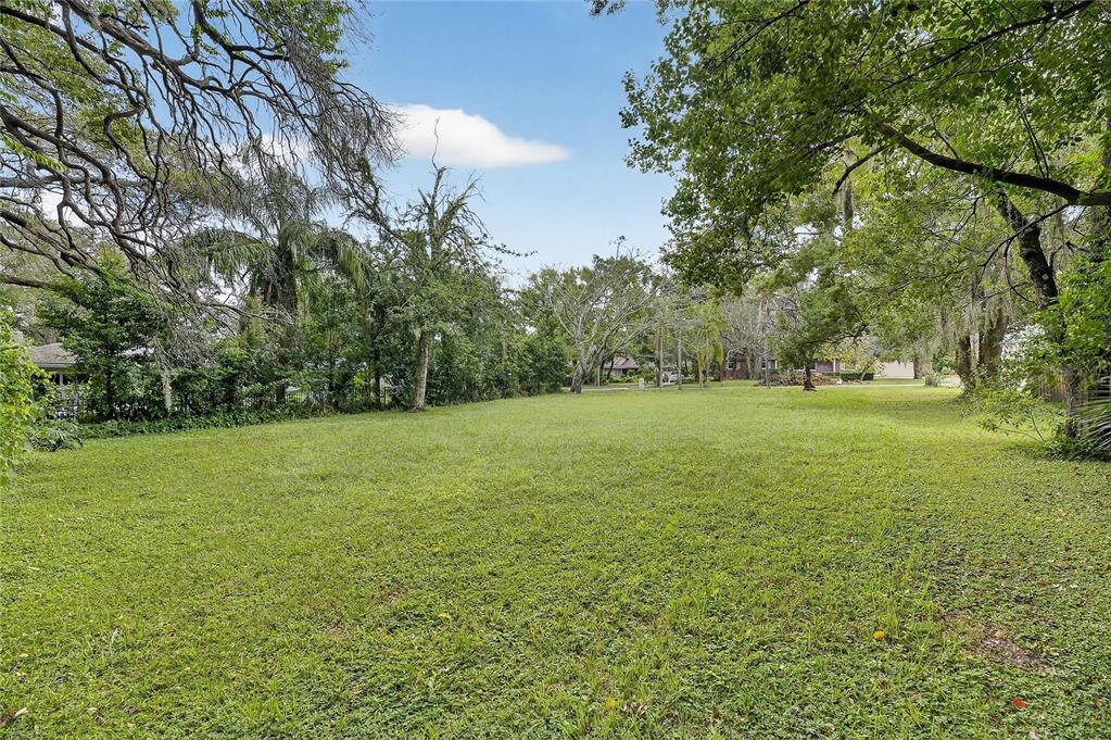 A large, grassy, tree-lined residential lot under a clear blue sky — 5208 E 122ND AVENUE, TEMPLE TERRACE, FL