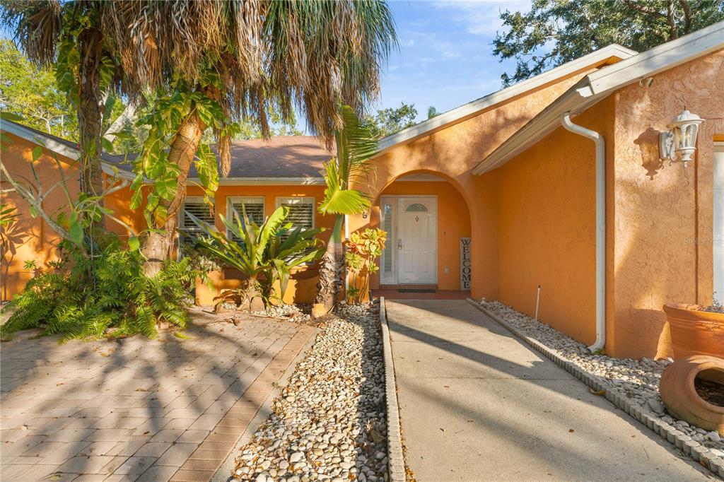 A walkway leads to the front entrance of a house with orange stucco exterior walls — 619 29TH STREET E, BRADENTON, FL