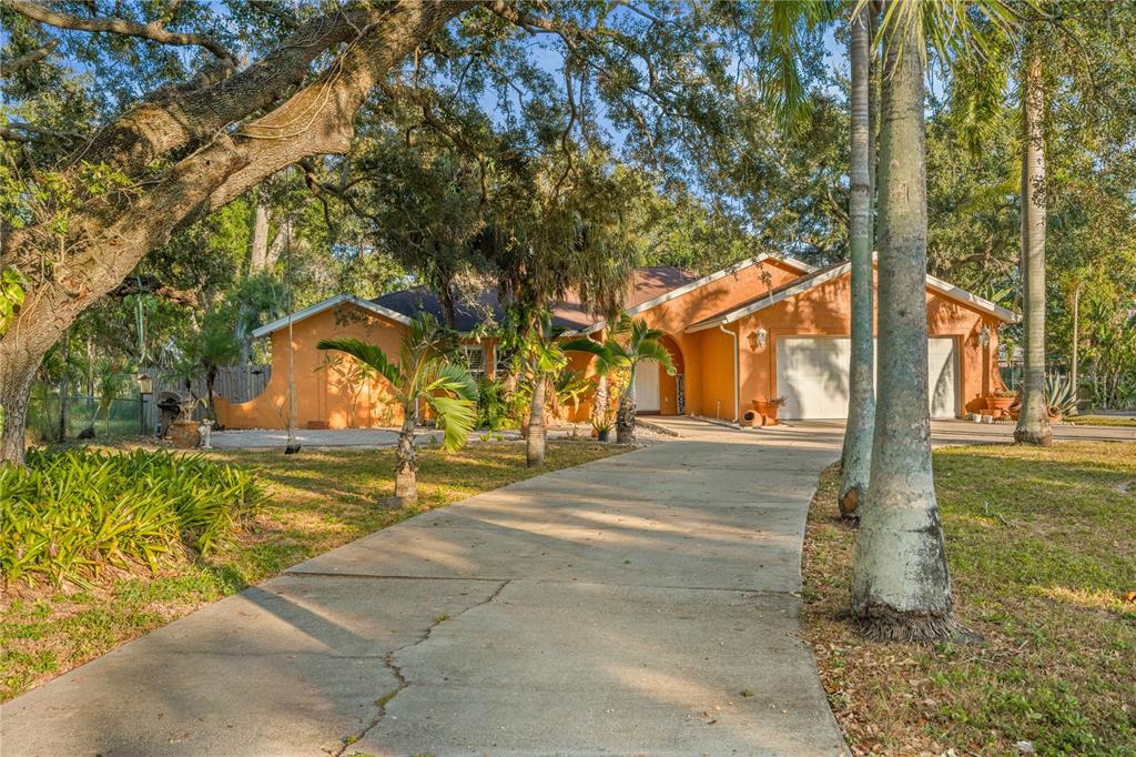 A single-story orange house with a concrete driveway and mature trees in the front yard — 619 29TH STREET E, BRADENTON, FL