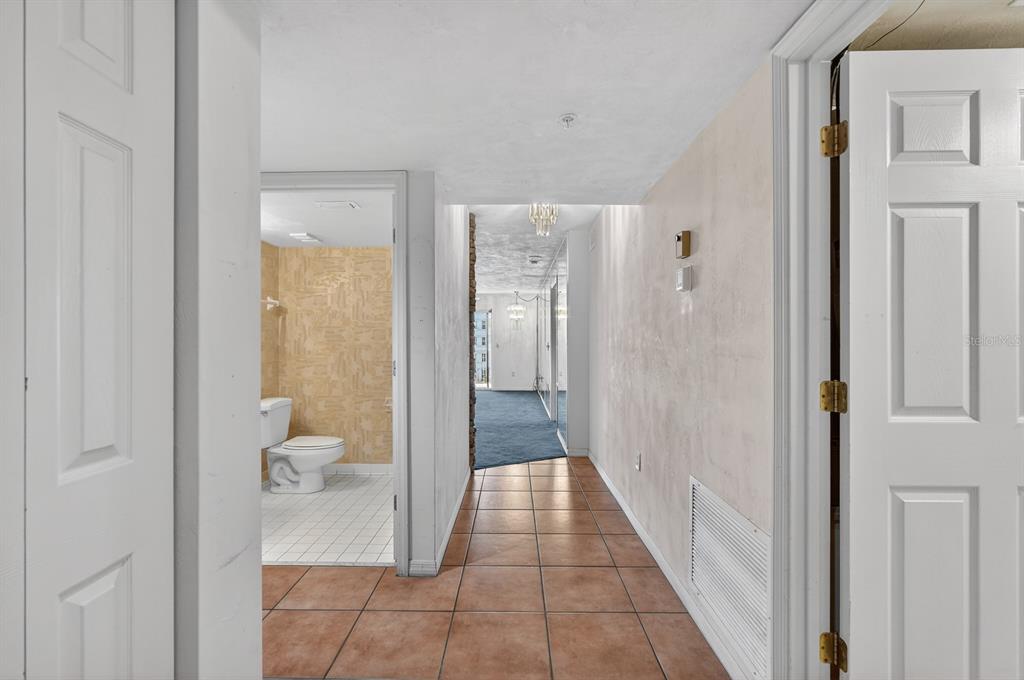 A tiled hallway leads past a bathroom with tan wallpaper toward a carpeted living area — 1 JOHN ANDERSON DRIVE UNIT 5150, ORMOND BEACH, FL