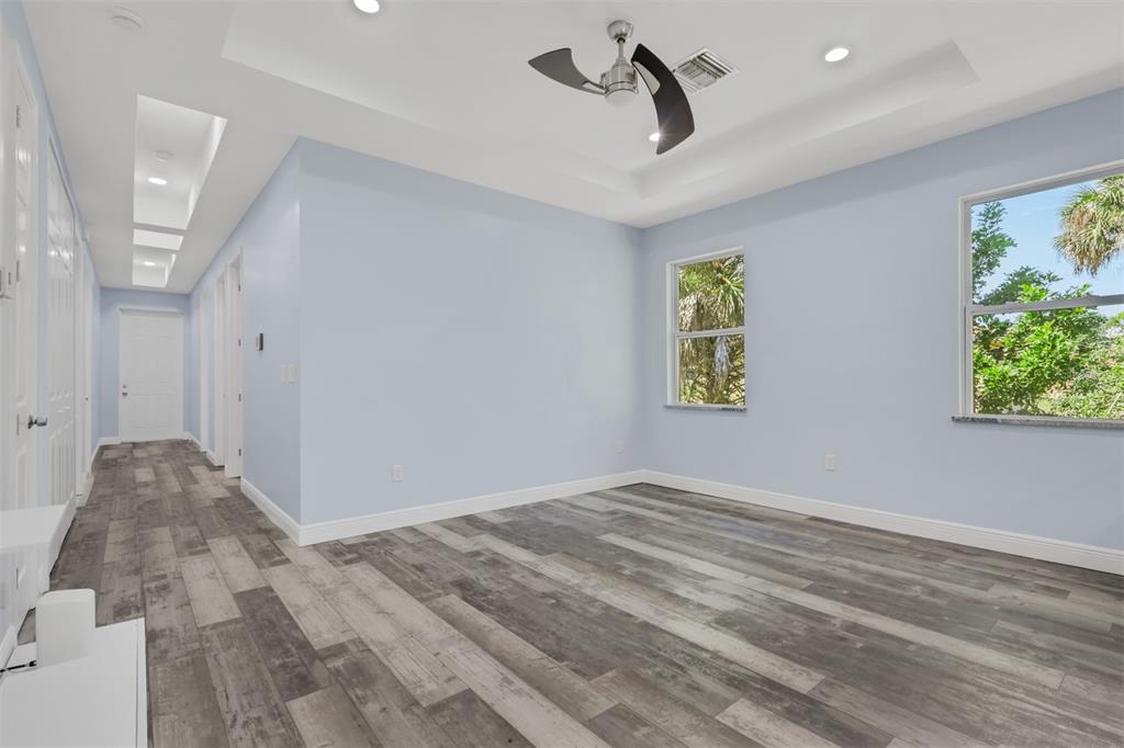 An empty bedroom features light blue walls, gray wood-look flooring, and a tray ceiling — 2977 4TH AVENUE SE, NAPLES, FL