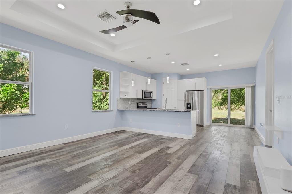 A kitchen and living area with light blue walls, gray wood-look flooring, and white cabinets — 2977 4TH AVENUE SE, NAPLES, FL