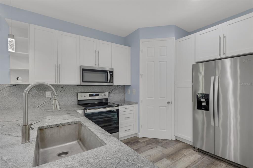 A kitchen features white cabinets, granite countertops, stainless steel appliances, and a stainless steel sink — 2977 4TH AVENUE SE, NAPLES, FL