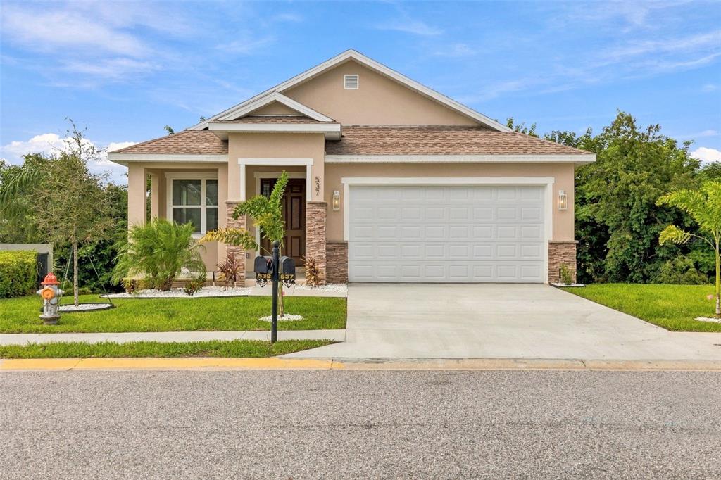 A single-story house with a white garage door, stone accents, and an unfinished dirt yard — 537 PINELOCH DRIVE, HAINES CITY, FL