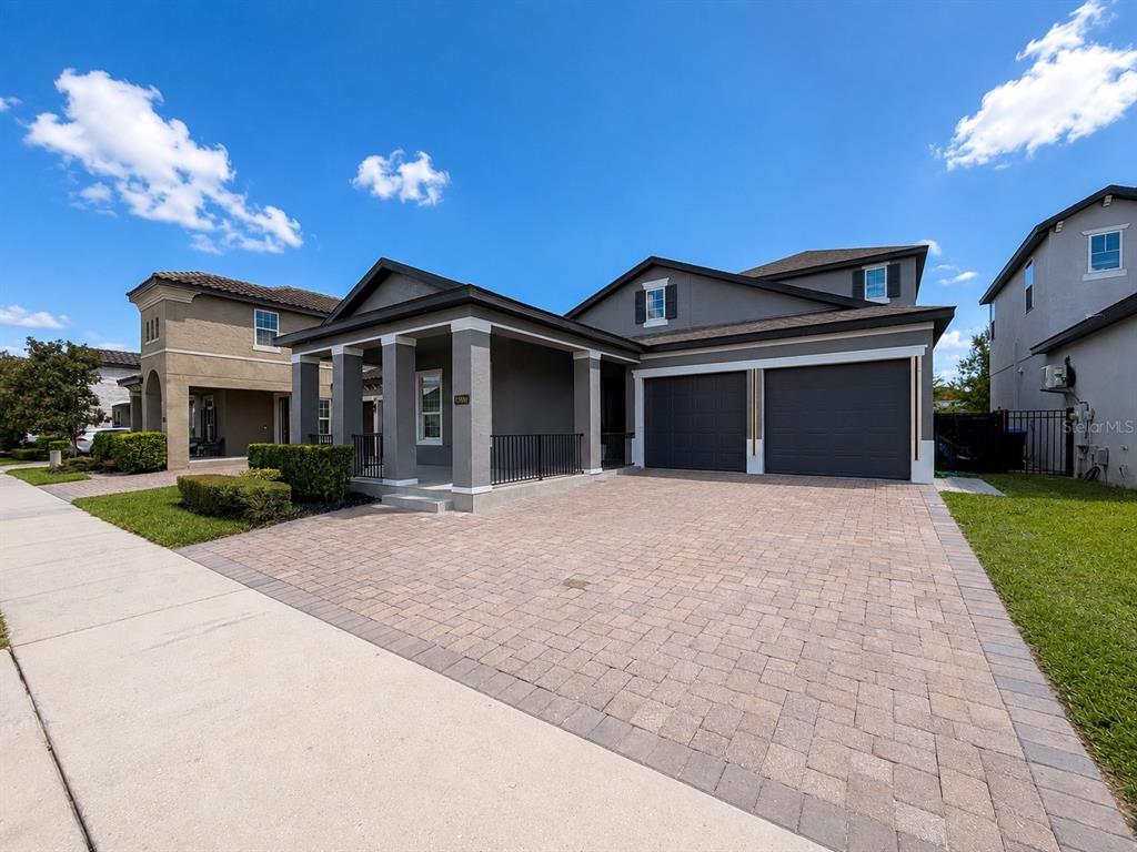 A two-story house with a gray exterior, a paved driveway, and a covered front porch — 12989 WESTSIDE VILLAGE LOOP, WINDERMERE, FL