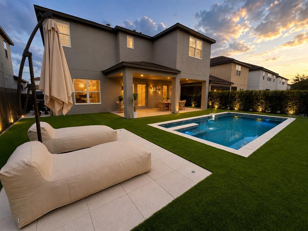 A two-story house with a backyard pool, artificial turf, and two lounge chairs under an umbrella — 12989 WESTSIDE VILLAGE LOOP, WINDERMERE, FL