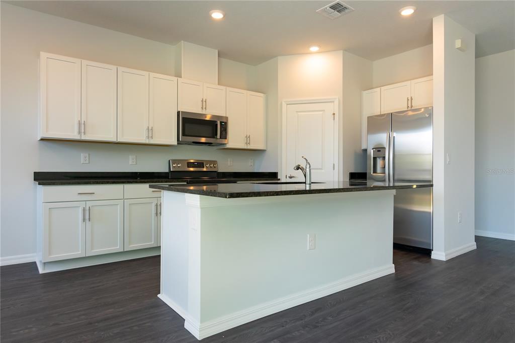 A kitchen with white cabinets, dark countertops, stainless steel appliances, and a central island — 1348 PALAU STREET SE, PALM BAY, FL